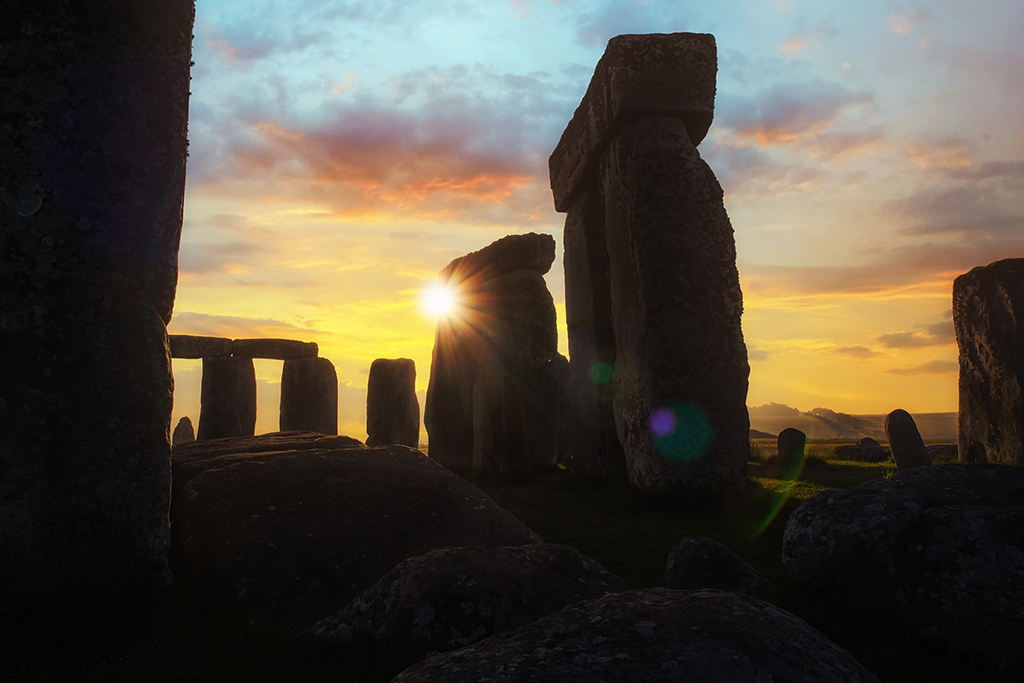 As dawn breaks over Stonehenge, the ancient stones stand silhouetted against the golden hues of the sunrise, a timeless testament to human ingenuity and the mysteries of the past. Wiltshire, England