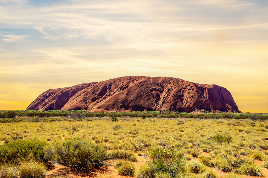 Uluru glowing in the golden hues of sunset; standing proudly in the heart of the Australian outback. The Red Center, Australia