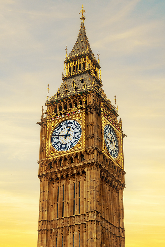 The iconic Elizabeth Tower, home to the Great Bell known as Big Ben, stands majestically against a golden sky in London, England.